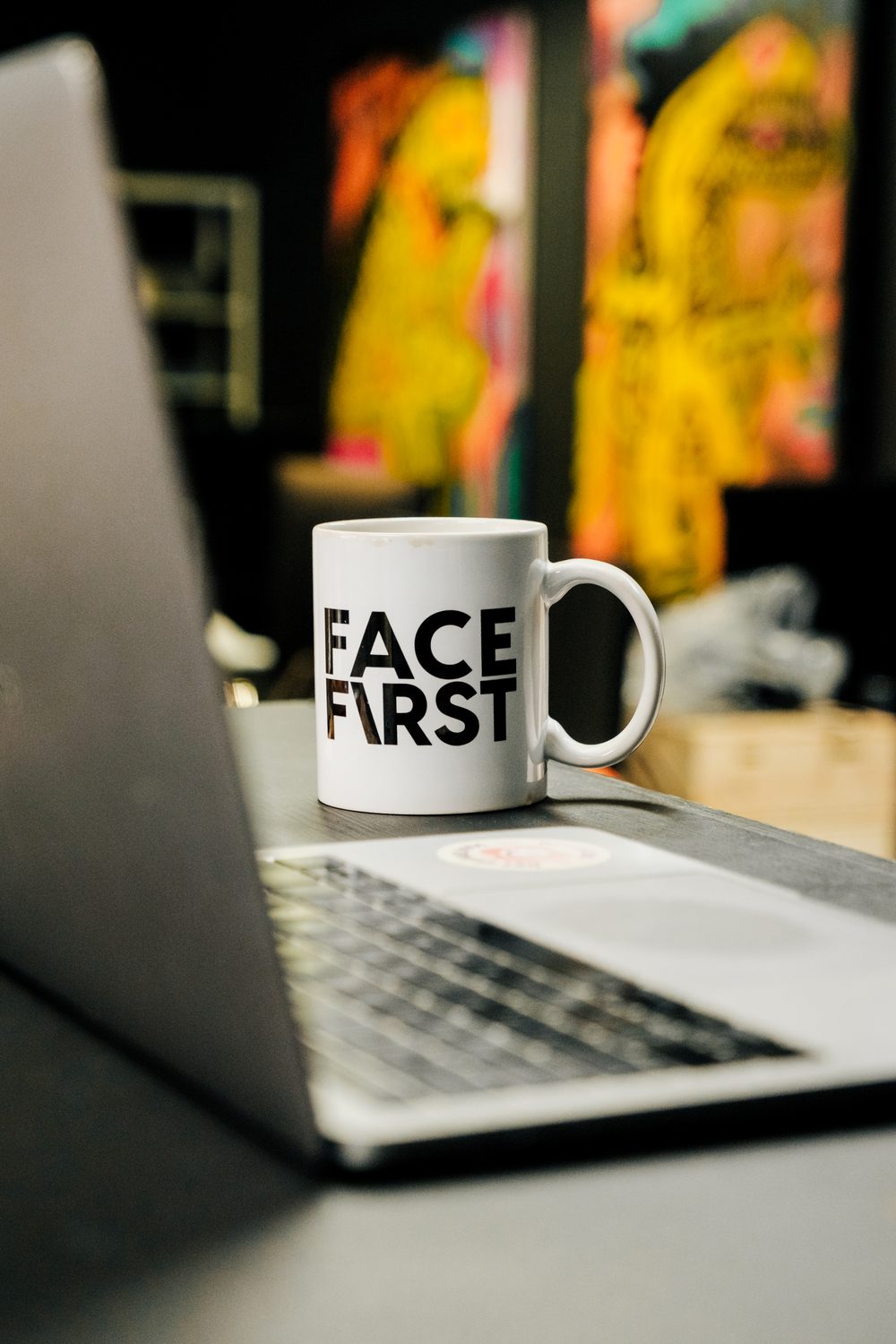 Facefirst-kopp ved siden av en laptop under redigering av innhold